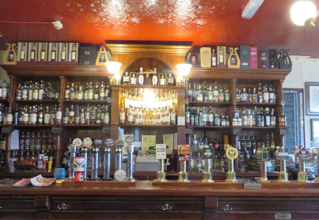 A wood fronted bar with ten beer fonts and dozens of bottles of whisky
