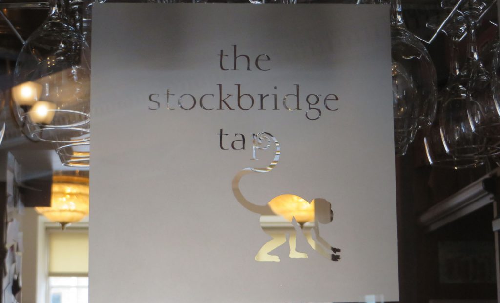 Etched glass screen with the words, the stockbridge tap and a silhouette of a long tailed monkey