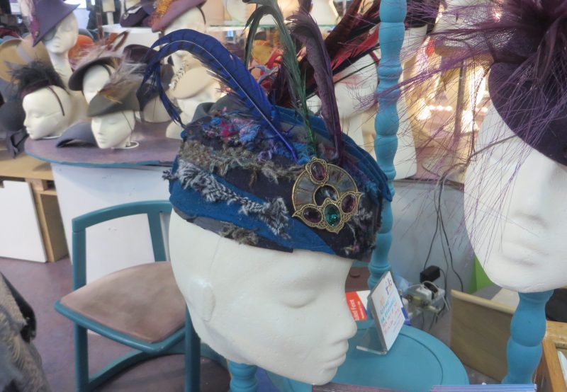 A blue and grey glengarry style hat with jewels and feathers