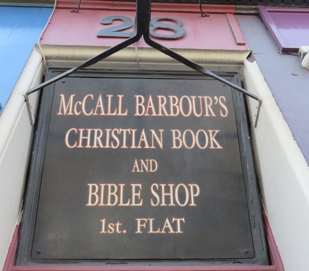 A sign above a door. The sign reads, McCall Barbour's Christian Book and Bible Shop. First flat.